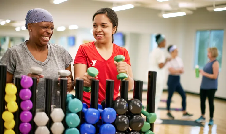 two women in a ymca fitness class pick up weights